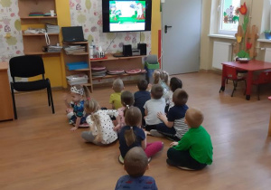 Dzieci oglądają i mawiają prezentację multimedialną na temat lasu.